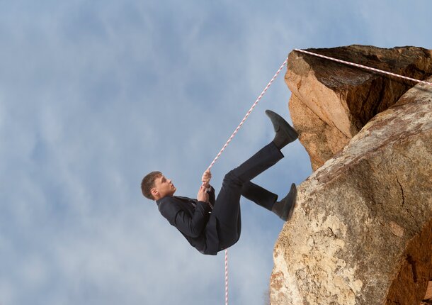 businessman scaling rock